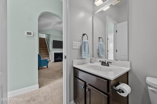 bathroom with vaulted ceiling, vanity, and toilet