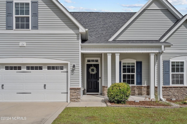 doorway to property featuring a porch, a lawn, and a garage