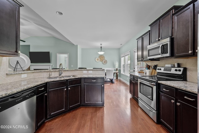 kitchen featuring lofted ceiling, hardwood / wood-style flooring, sink, hanging light fixtures, and appliances with stainless steel finishes