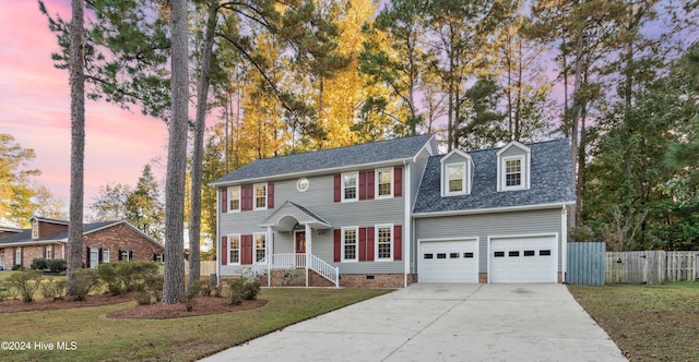 colonial home with a yard and a garage