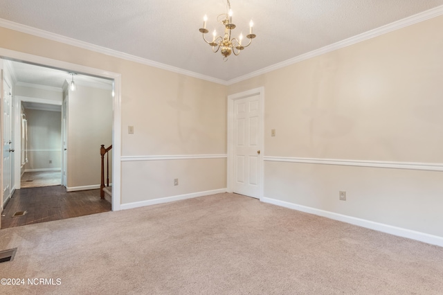 spare room with carpet flooring, a textured ceiling, ornamental molding, and an inviting chandelier