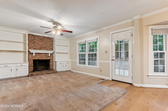 unfurnished living room featuring light hardwood / wood-style floors, a textured ceiling, plenty of natural light, and a fireplace