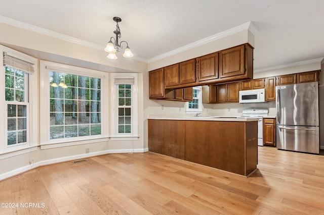 kitchen with plenty of natural light, light wood-type flooring, pendant lighting, and white appliances