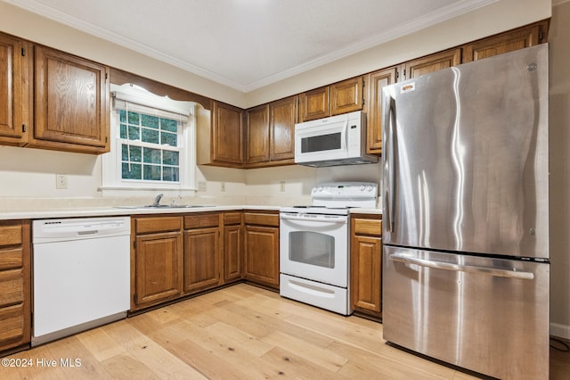 kitchen featuring sink, crown molding, light hardwood / wood-style floors, and white appliances