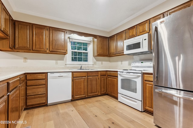 kitchen with ornamental molding, sink, light wood-type flooring, and white appliances