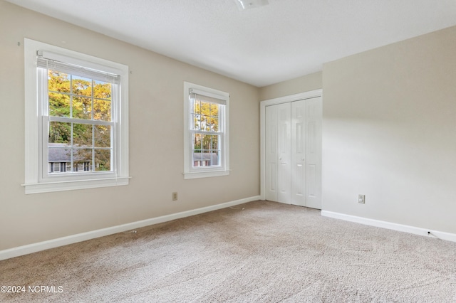 unfurnished bedroom featuring multiple windows, a closet, and carpet flooring