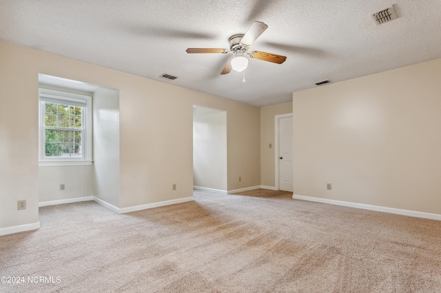 empty room featuring light carpet, a textured ceiling, and ceiling fan