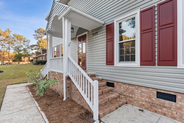 entrance to property with a porch and a lawn