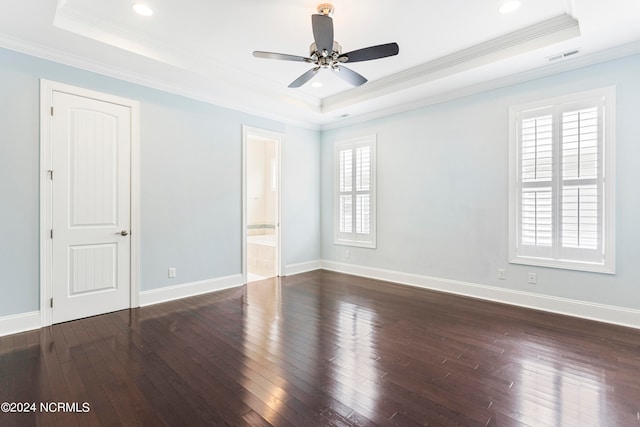 spare room featuring a raised ceiling, dark hardwood / wood-style floors, and ornamental molding