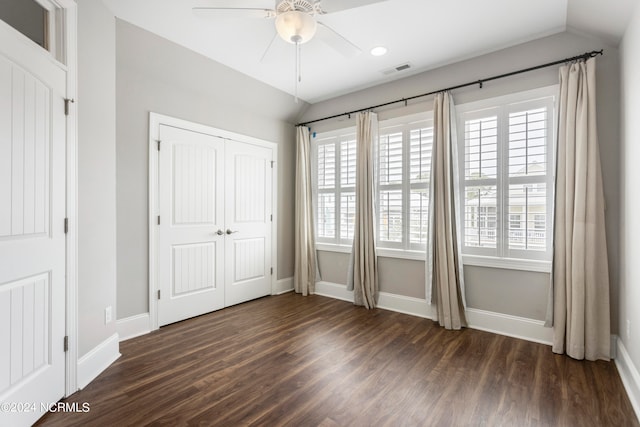 unfurnished bedroom with lofted ceiling, ceiling fan, a closet, and dark hardwood / wood-style flooring