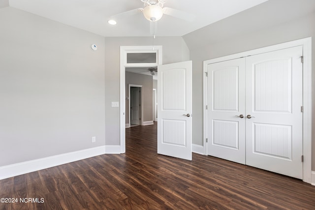 unfurnished bedroom featuring ceiling fan, a closet, dark wood-type flooring, and lofted ceiling