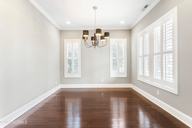 unfurnished dining area featuring dark wood-type flooring, ornamental molding, a notable chandelier, and a wealth of natural light