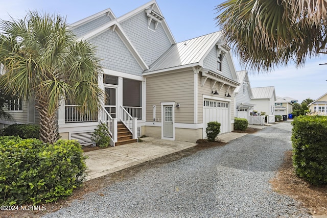 1230 Pinfish Ln, Carolina Beach, NC 28428 - view of front of house with a garage, a sunroom, a metal roof, and driveway