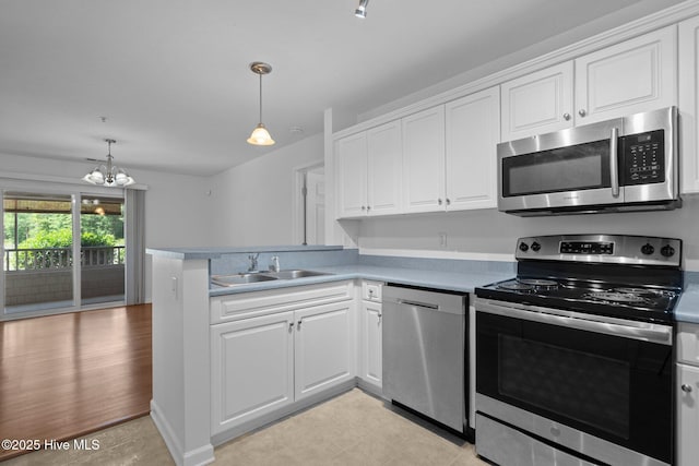 633 Spencer Farlow Dr Unit 12, Carolina Beach, NC 28428 - kitchen with stainless steel appliances, a sink, white cabinets, and a chandelier