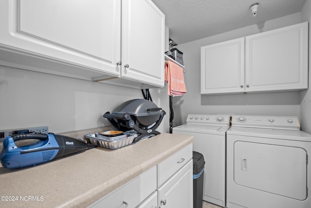 laundry area with separate washer and dryer, cabinets, and a textured ceiling