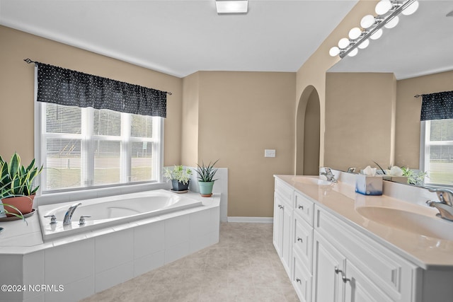 bathroom featuring tile patterned floors, plenty of natural light, tiled tub, and vanity