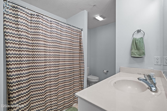 bathroom featuring a textured ceiling, vanity, and toilet