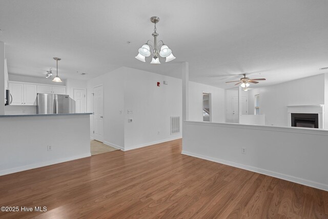 633 Spencer Farlow Dr Unit 12, Carolina Beach, NC 28428 - unfurnished living room featuring light wood finished floors, baseboards, a ceiling fan, a chandelier, and a fireplace