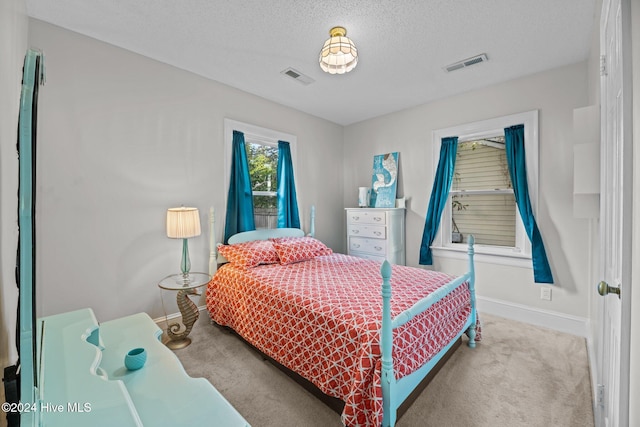 bedroom with a textured ceiling and light colored carpet