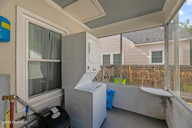 laundry area with crown molding, a healthy amount of sunlight, and stacked washer and dryer