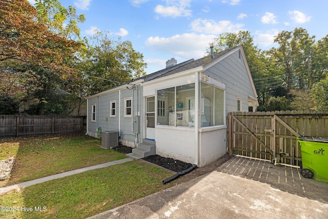 view of front facade with a sunroom, cooling unit, and a front lawn