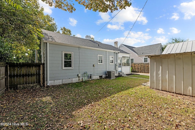 back of property with a shed, central AC, and a lawn