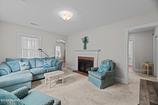 carpeted living room with a brick fireplace and a textured ceiling