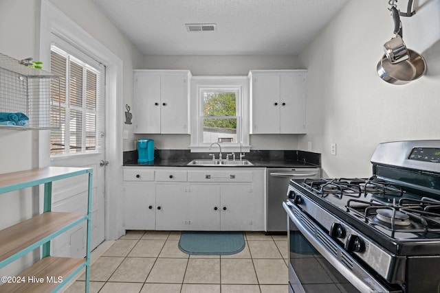 kitchen featuring light tile patterned floors, white cabinetry, a textured ceiling, sink, and stainless steel appliances