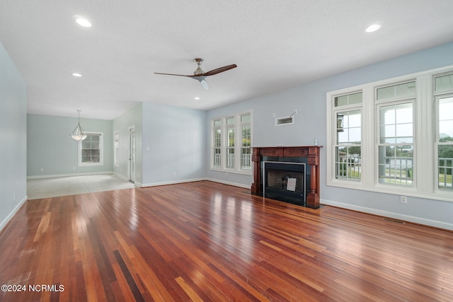 unfurnished living room featuring a textured ceiling, ceiling fan, wood-type flooring, and a wealth of natural light