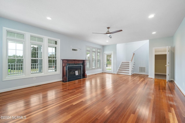 unfurnished living room with a textured ceiling, a healthy amount of sunlight, wood-type flooring, and ceiling fan