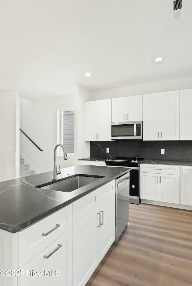 kitchen with white cabinets, hardwood / wood-style floors, stainless steel appliances, and sink