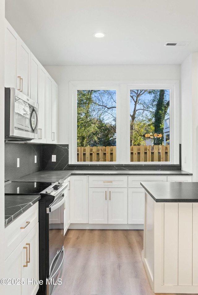 kitchen featuring tasteful backsplash, a wealth of natural light, white cabinets, and stainless steel appliances