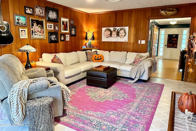 living room featuring crown molding, light hardwood / wood-style flooring, and wooden walls