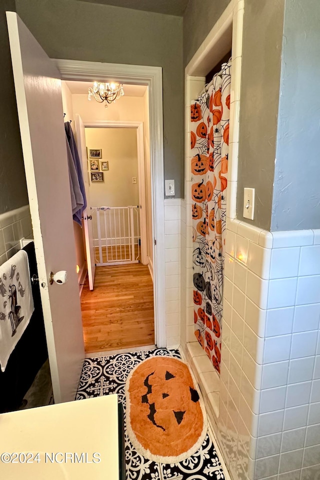 bathroom featuring hardwood / wood-style floors, walk in shower, and tile walls