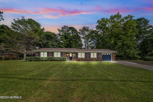 single story home featuring a lawn and a garage