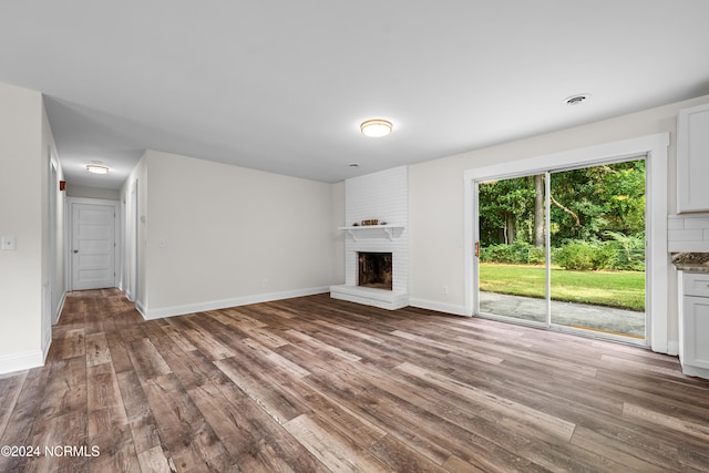 unfurnished living room featuring a brick fireplace and hardwood / wood-style floors