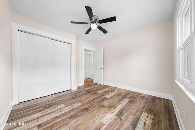 unfurnished bedroom featuring ceiling fan, hardwood / wood-style flooring, and a closet