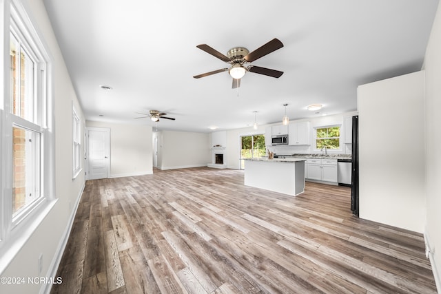 unfurnished living room with light wood-type flooring, ceiling fan, and sink