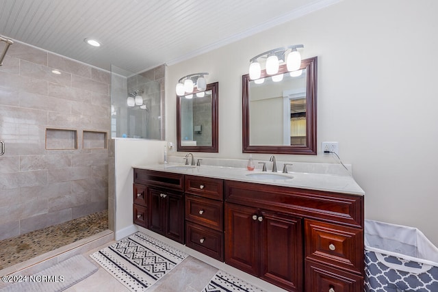 full bath featuring tile patterned flooring, a sink, tiled shower, double vanity, and crown molding