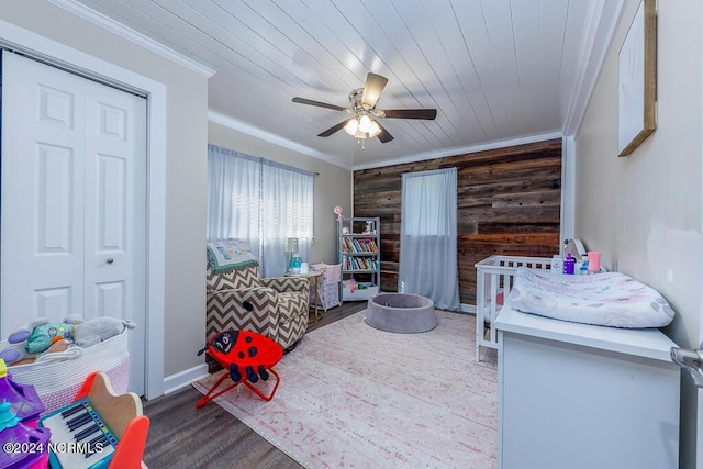 bedroom with ceiling fan, wooden walls, wood finished floors, wood ceiling, and crown molding