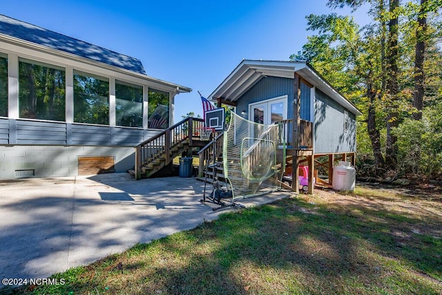 rear view of house with stairway, a patio area, a wooden deck, and a sunroom