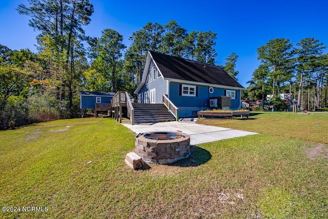 back of property with a wooden deck, a fire pit, a patio, stairway, and a yard