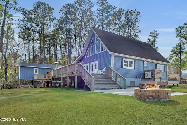 rear view of house with a fire pit, a deck, stairway, and a lawn