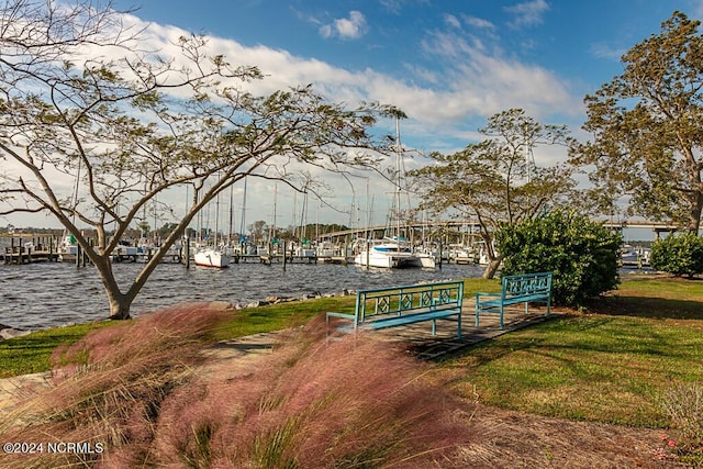 surrounding community featuring a dock, a water view, and a lawn