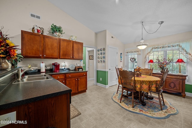 kitchen featuring pendant lighting, a textured ceiling, sink, and high vaulted ceiling