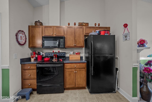 kitchen featuring light tile patterned flooring, black appliances, and vaulted ceiling