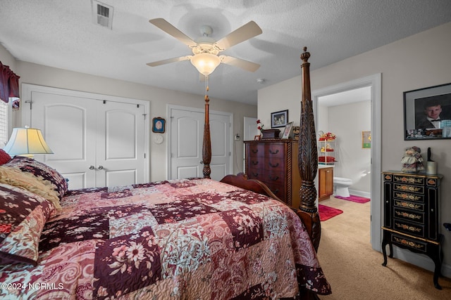 bedroom featuring a textured ceiling, ensuite bathroom, ceiling fan, and light colored carpet