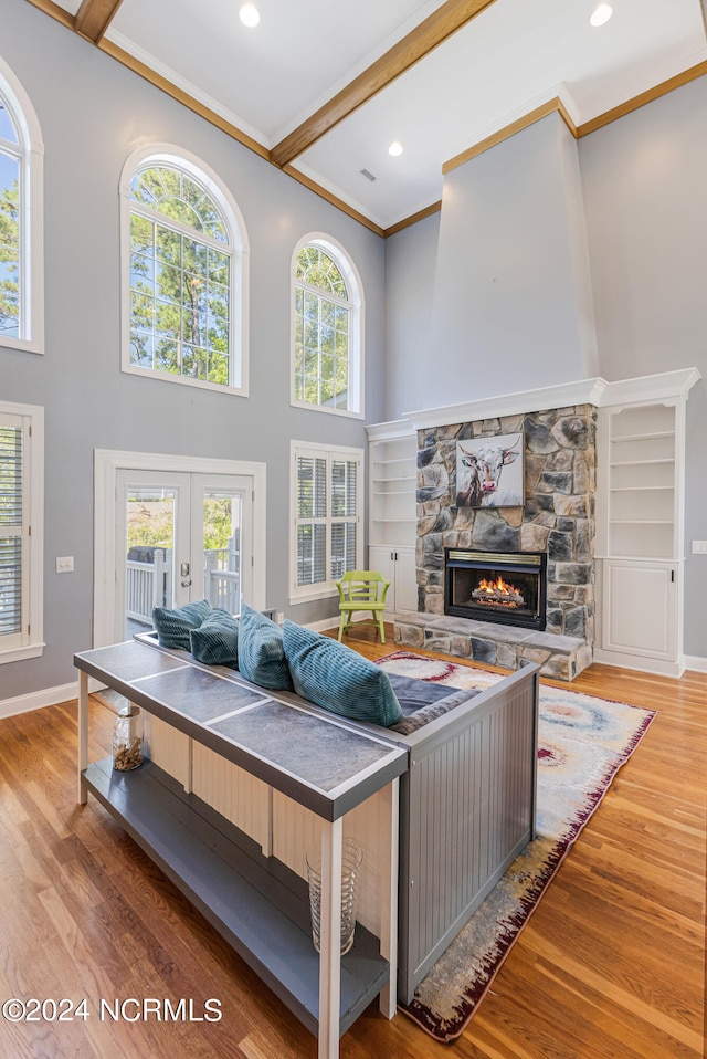 living room featuring crown molding, wood-type flooring, beamed ceiling, and a fireplace