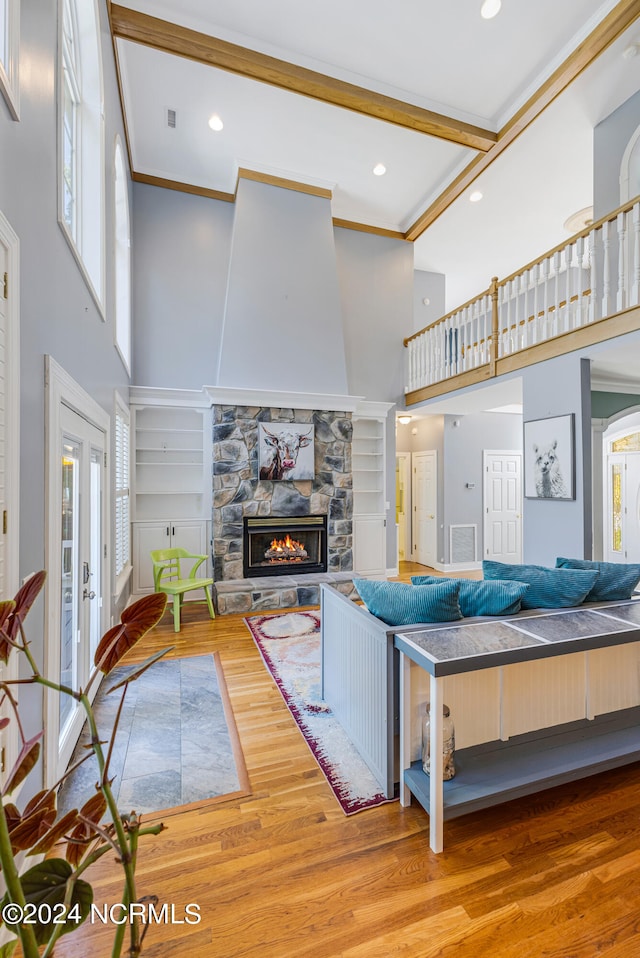 living room featuring french doors, a stone fireplace, hardwood / wood-style flooring, and a towering ceiling