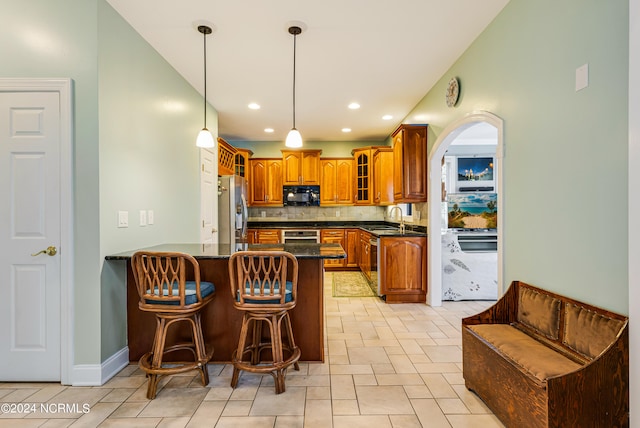 kitchen featuring decorative backsplash, kitchen peninsula, sink, a breakfast bar, and appliances with stainless steel finishes